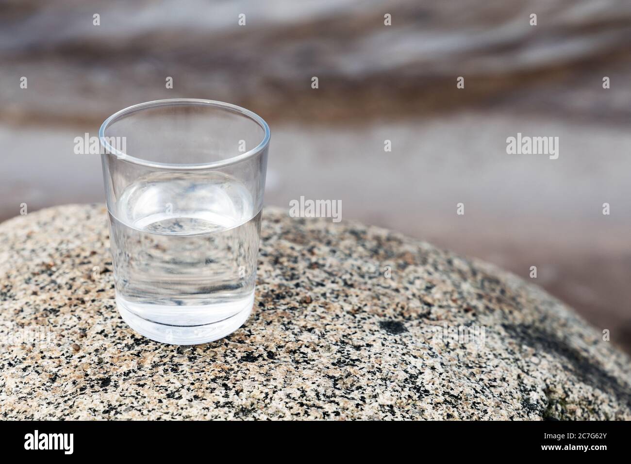 Un bicchiere di acqua pulita si trova sulla pietra costiera. Primo piano con la messa a fuoco morbida selettiva Foto Stock Un bicchiere di acqua pulita si trova sulla pietra costiera. Primo piano con la messa a fuoco morbida selettiva Foto Stock