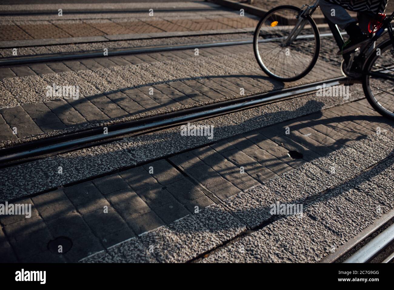 Ombra di una bicicletta tesa sopra la ferrovia su un strada lastricata Foto Stock