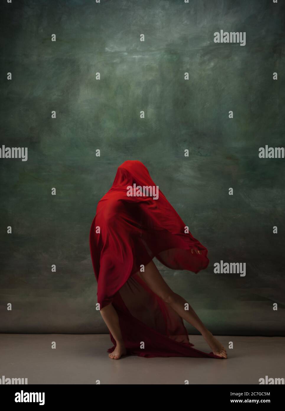 Ali che volano. Ballerina classica e graziosa che balla su sfondo scuro dello studio. Panno rosso profondo. Il concetto di grazia, artista, movimento, azione e movimento. Aspetto senza peso, flessibile. Moda, stile. Foto Stock