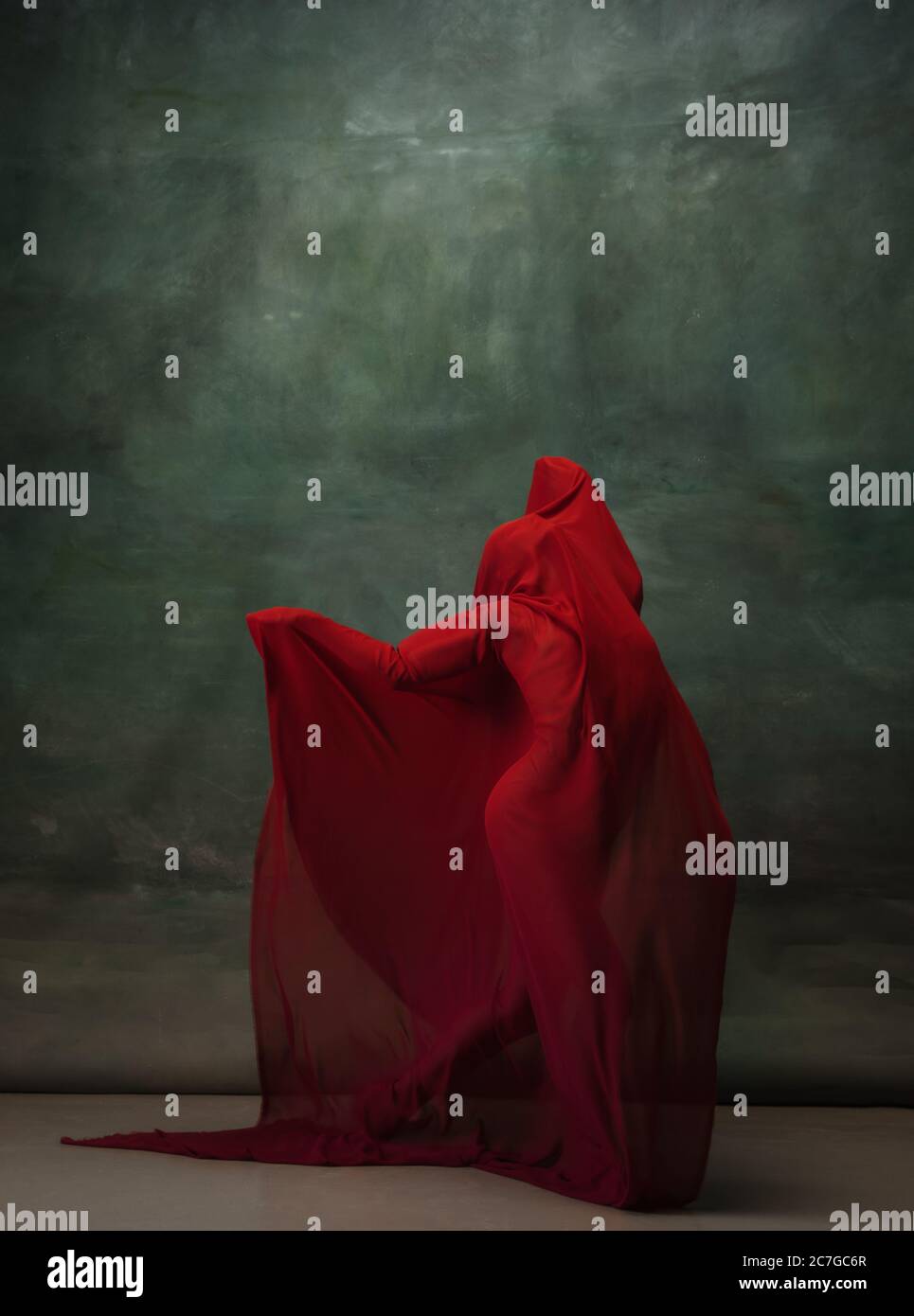 Ali che volano. Ballerina classica e graziosa che balla su sfondo scuro dello studio. Panno rosso profondo. Il concetto di grazia, artista, movimento, azione e movimento. Aspetto senza peso, flessibile. Moda, stile. Foto Stock