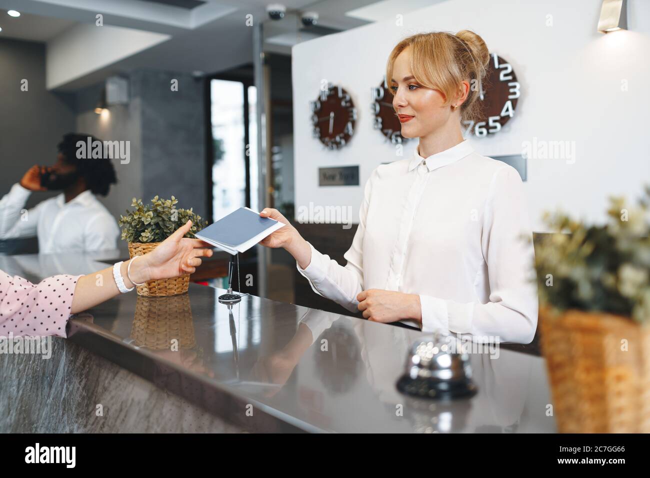 La donna della reception dell'hotel porta il passaporto dell'ospite per il check in Foto Stock