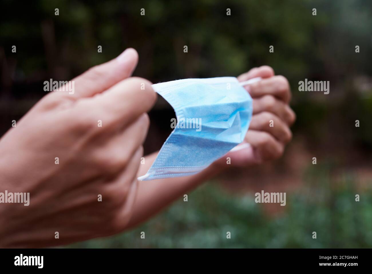 primo piano di un giovane contadino che sta per indossare una maschera chirurgica in un frutteto biologico Foto Stock