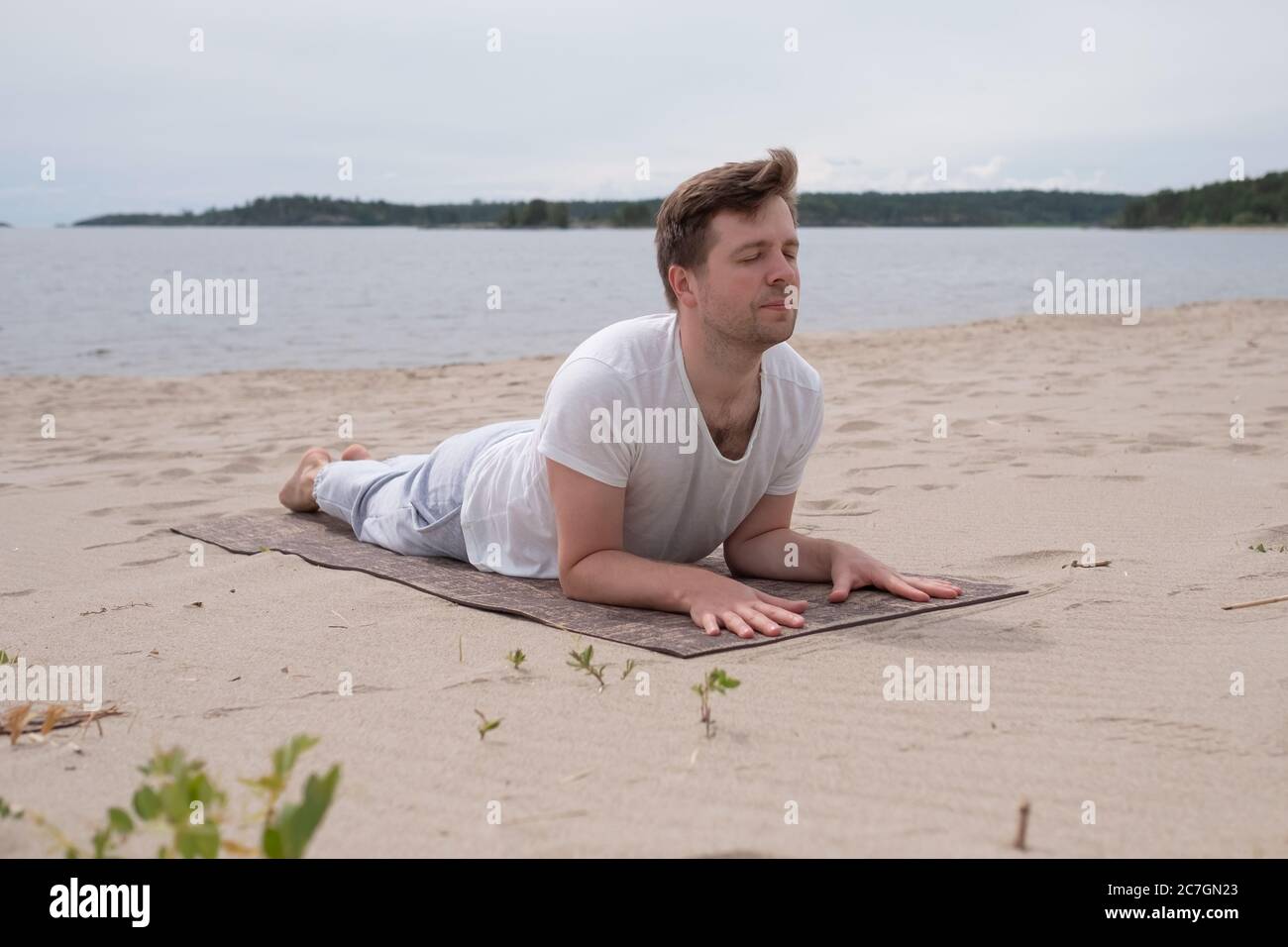 Uomo che fa il Cobra Yoga stretch su tappetino yoga Foto Stock
