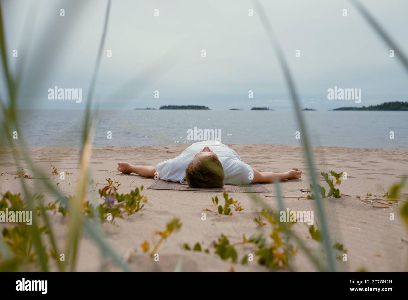 Giovane uomo che fa yoga su un lago in una giornata estiva, meditazione, relax posa Foto Stock