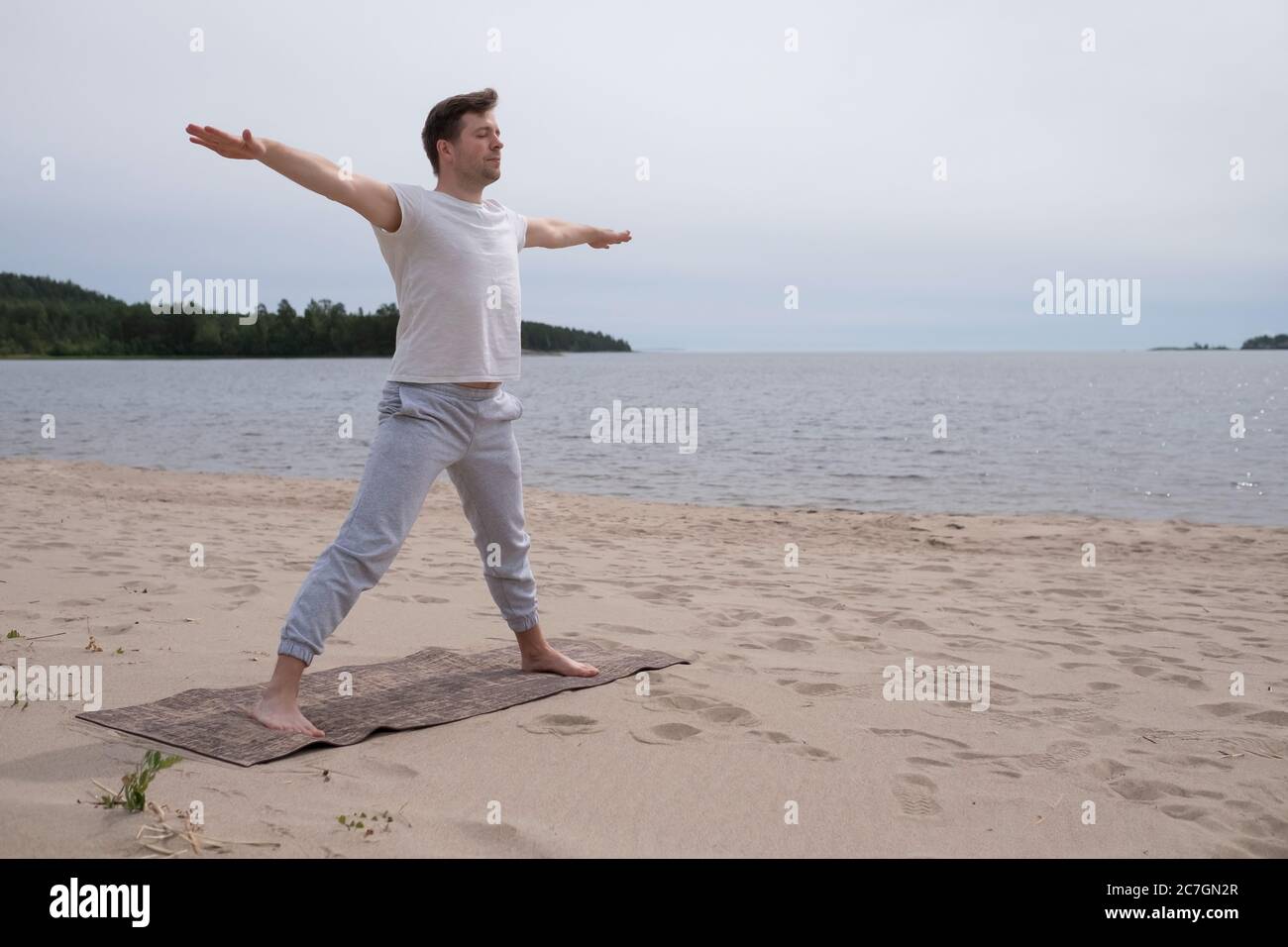 Giovane caucasico che pratica yoga all'aperto sulla spiaggia di sabbia Foto Stock