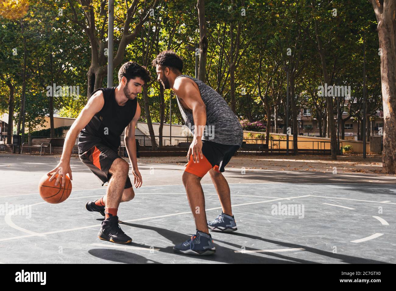 due giovani uomini che giocano a basket all'aperto lottano per la palla Foto Stock