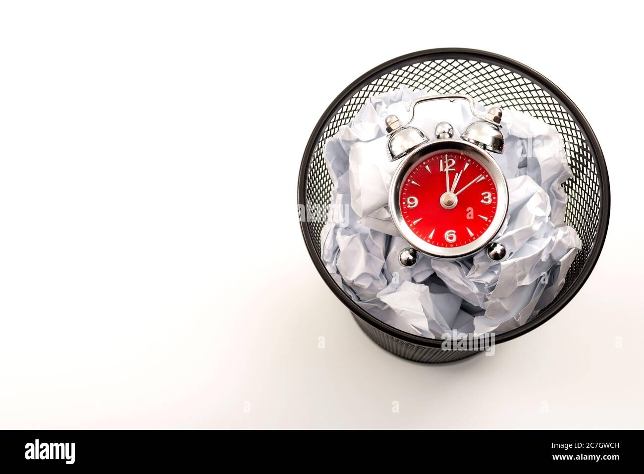Procrastination è il nemico della produttività e smettere di perdere tempo concetto tema con un orologio in un cestino nero rifiuti o cestino rifiuti accanto a sminuzzato Foto Stock