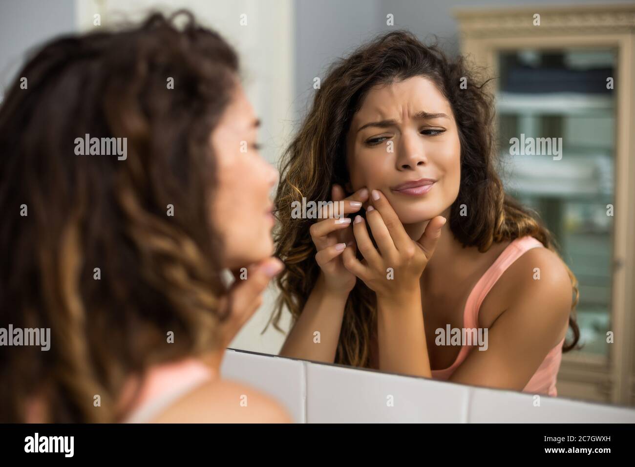 Bella donna che strizza pimple in bagno. Foto Stock