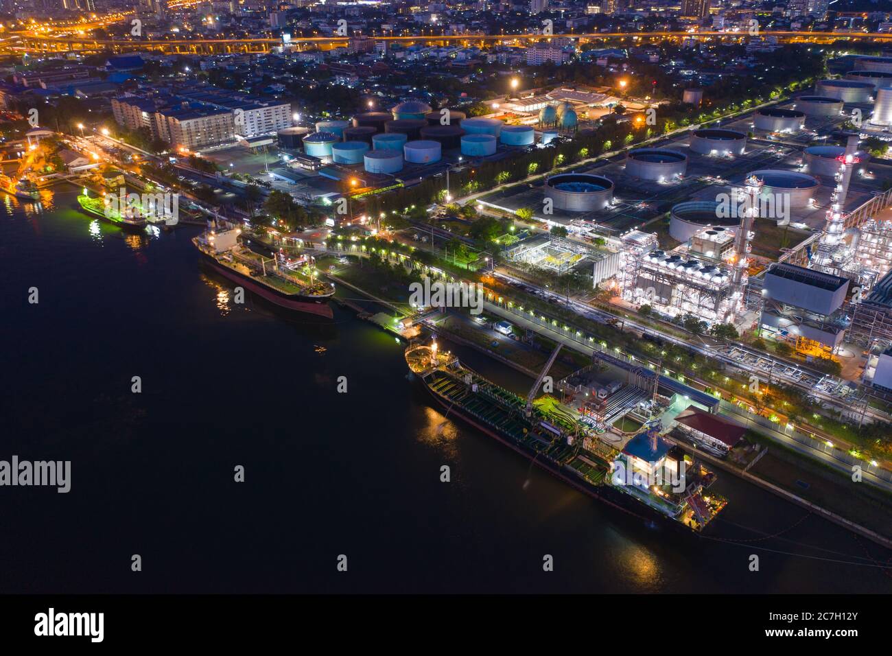 Vista aerea industriale di petrolio e gas, fabbrica di raffineria serbatoio di stoccaggio olio e tubi in acciaio con nave di trasporto di notte Foto Stock