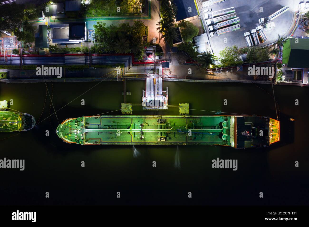 Vista aerea industriale di petrolio e gas, fabbrica di raffineria serbatoio di stoccaggio olio e tubi in acciaio con nave di trasporto di notte Foto Stock