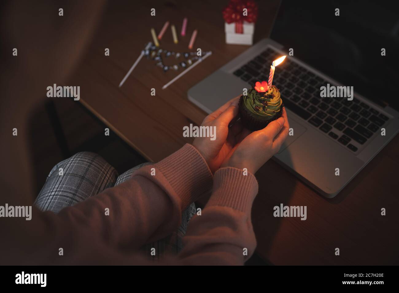 Donna asiatica che festeggia il compleanno di un collega con una videochiamata virtuale a casa mentre è isolata, resta a casa. Torta della tazza con la mano si accende Foto Stock