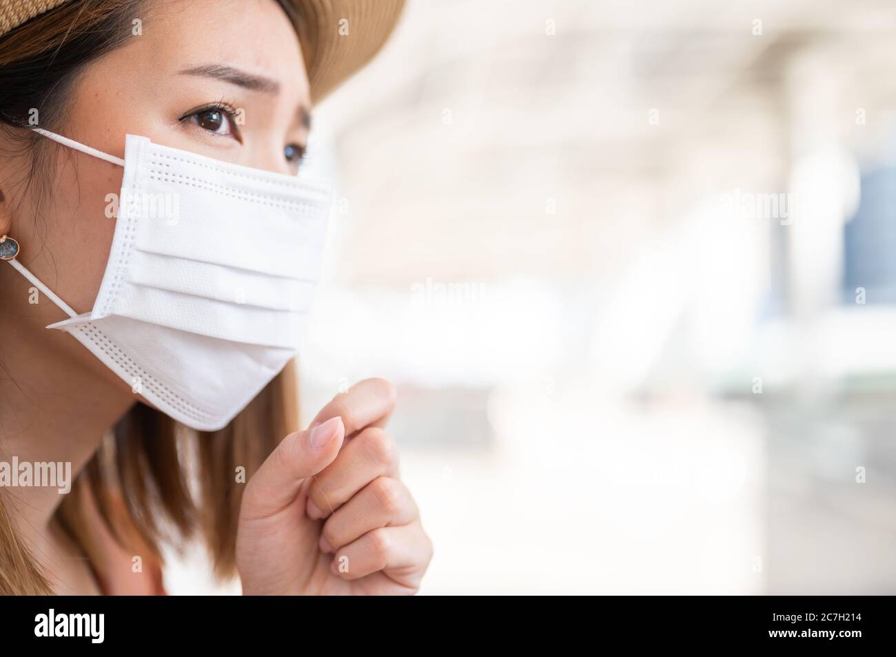 Ritagliare l'immagine di una giovane donna che indossa una maschera di protezione contro Coronavirus in pubblico Foto Stock