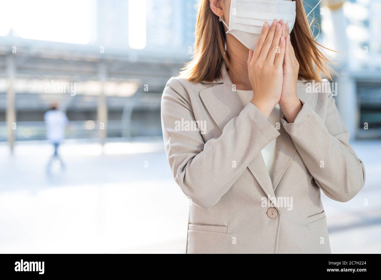 Immagine di raccolto di giovane donna di affari che indossa maschera di protezione contro Coronavirus in pubblico Foto Stock