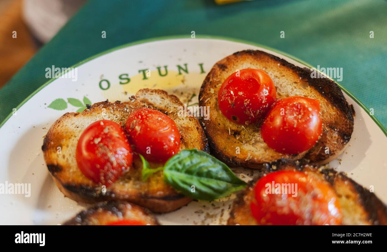 Ostuni, Italia - 14 agosto 2014: Bruschetta, ricetta italiana della dieta mediterranea. Pane tostato con pomodori ciliegini, basilico e oliv extra vergine Foto Stock