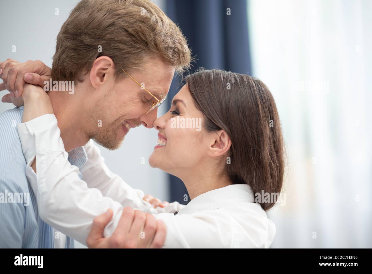 Coppia felice guardarsi l'un l'altro con amore. Primo piano di dolce gioioso uomo e donna che si toccano i nasi dell'altro a casa al chiuso Foto Stock