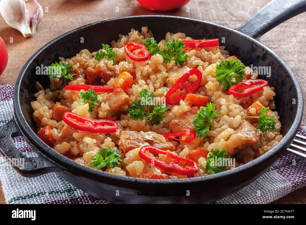 Riso con carne, verdure e prezzemolo in una padella Foto Stock