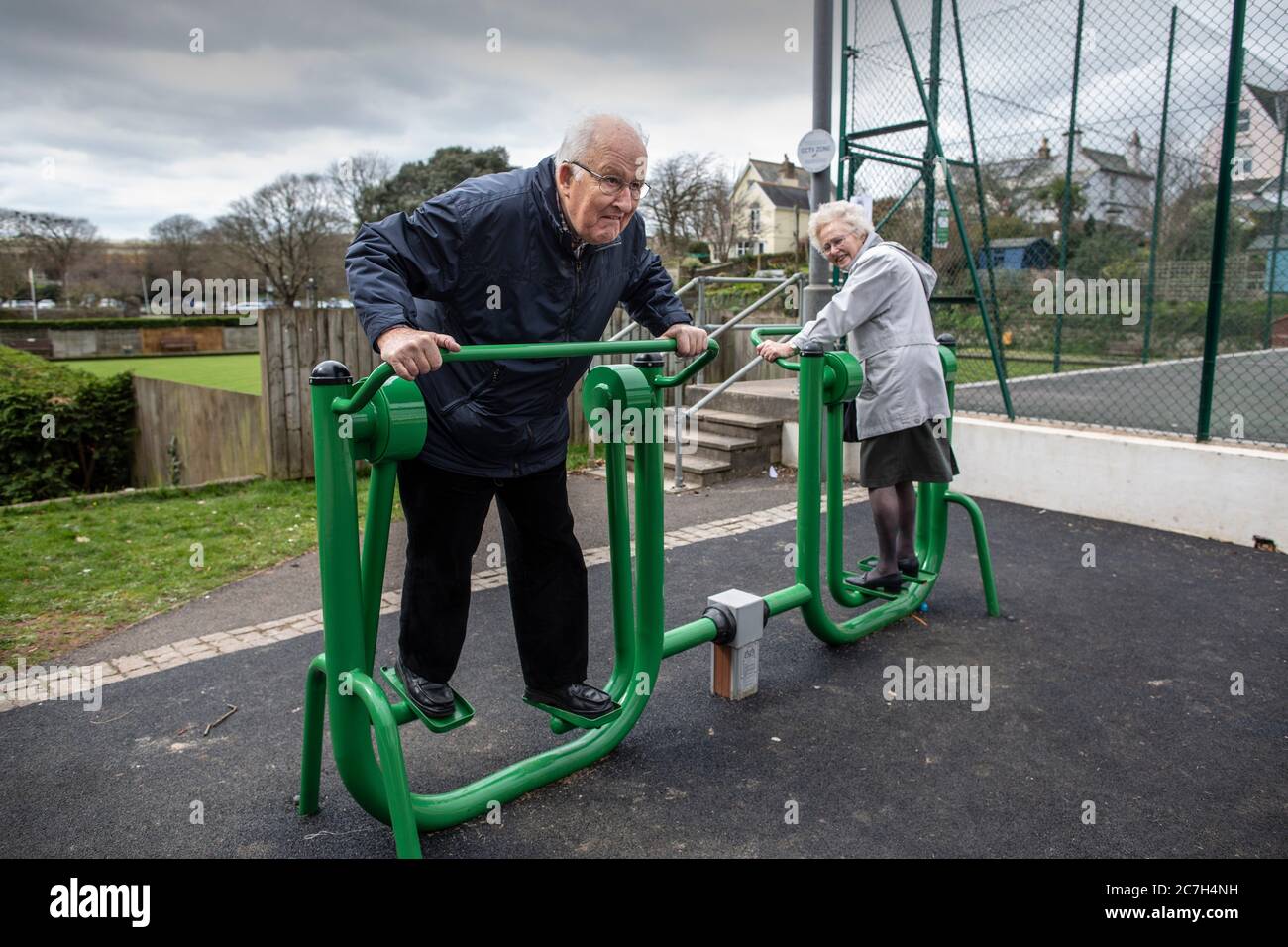 Coppie anziane negli anni ottanta in un parco di esercizi che provano insieme l'apparecchio, Kingsbridge, Devon, Inghilterra, Regno Unito Foto Stock