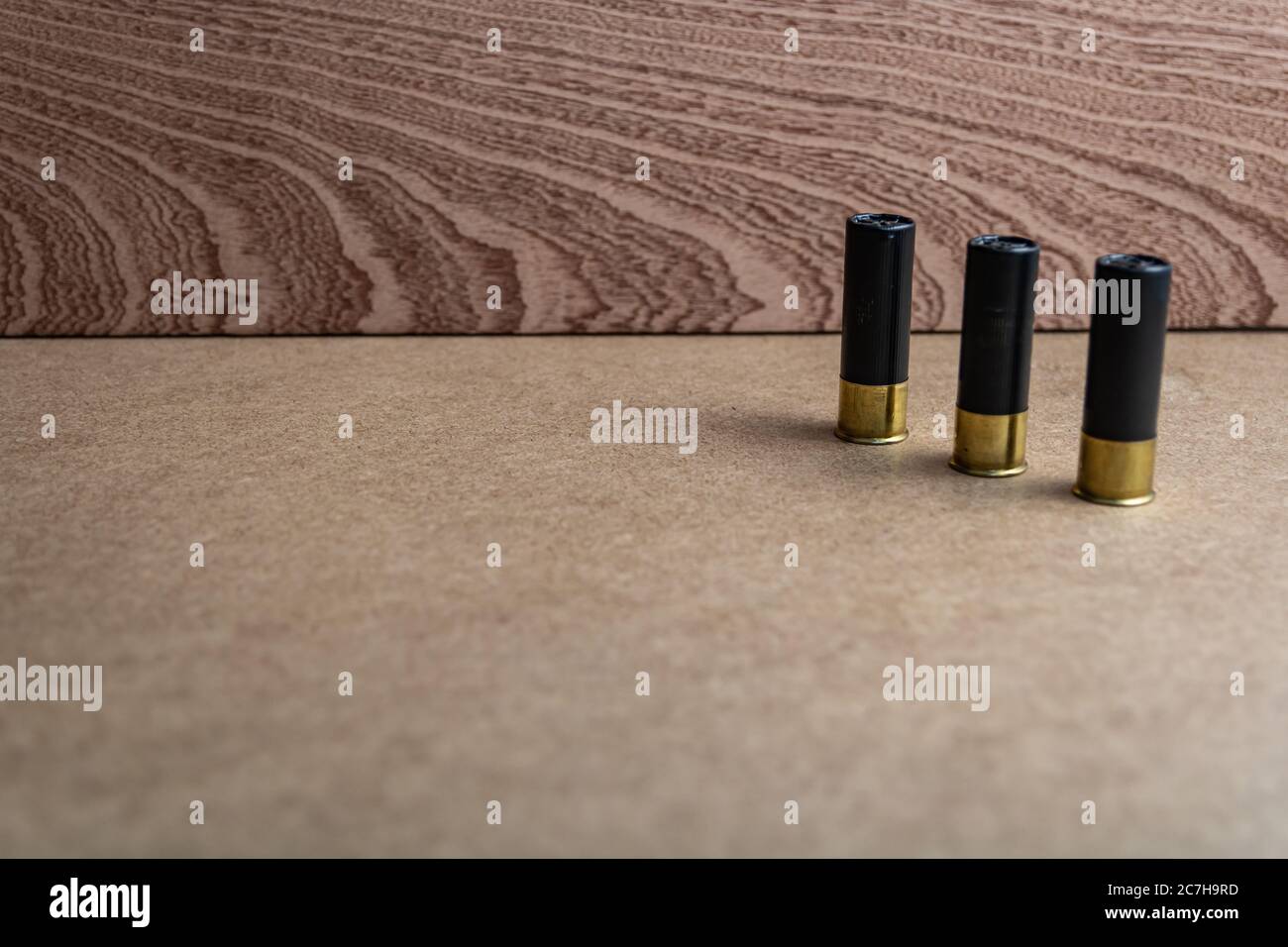 Messa a fuoco selettiva di tre gusci fucili neri su un superficie marrone Foto Stock