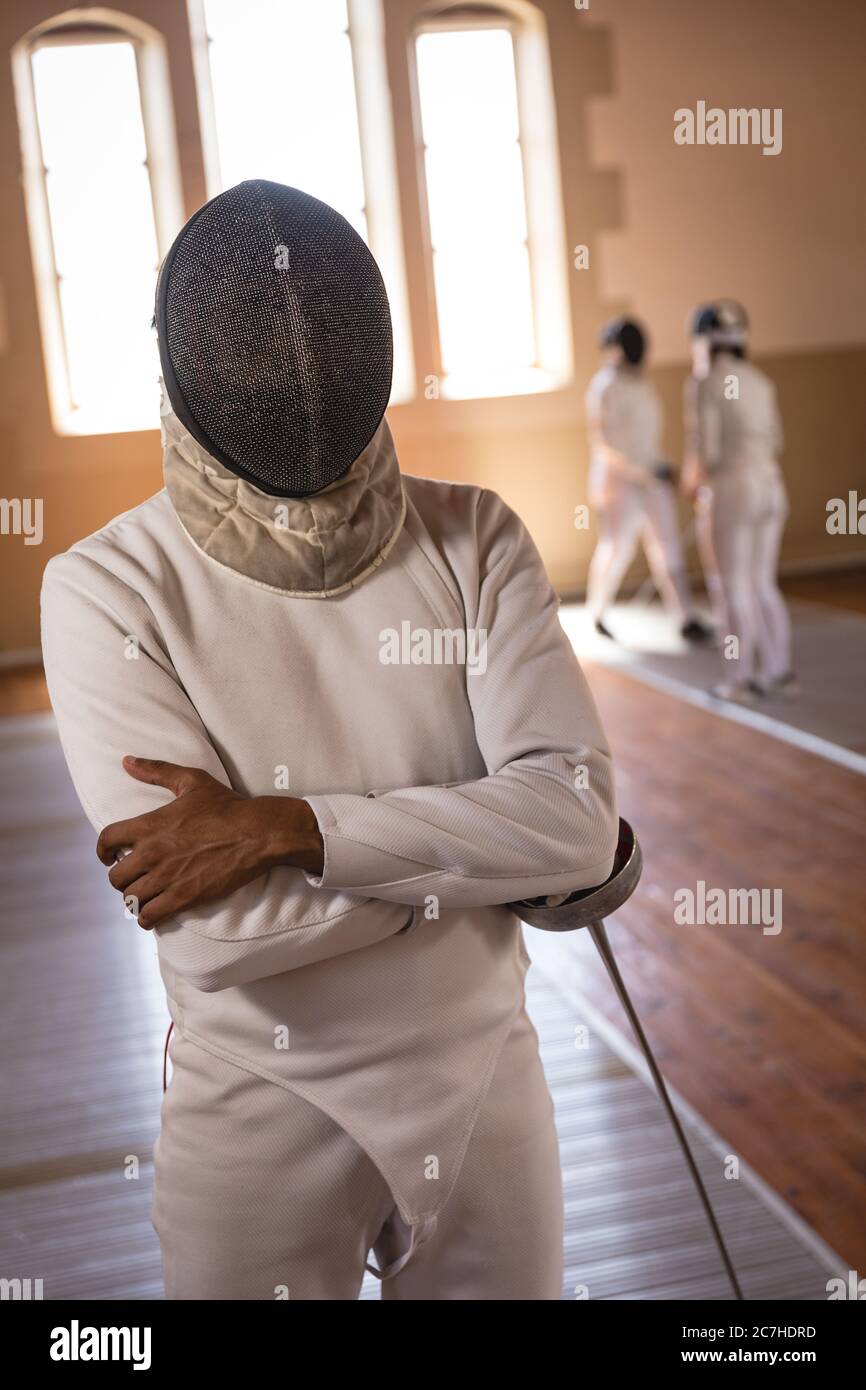 Uomo che indossa una maschera di scherma in piedi con le mani piegate Foto Stock