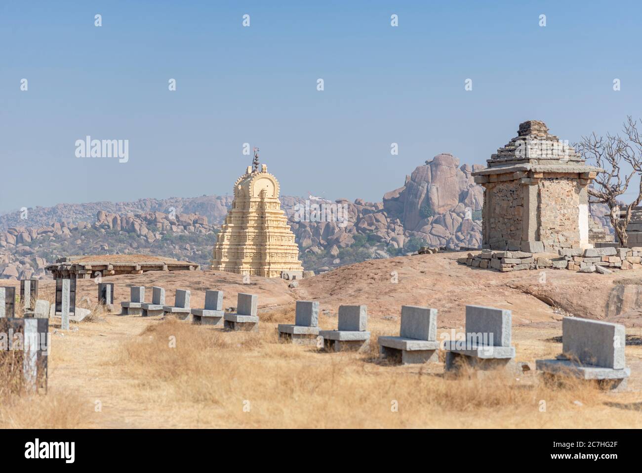 Panchine di pietra su collina con tempio sullo sfondo Foto Stock