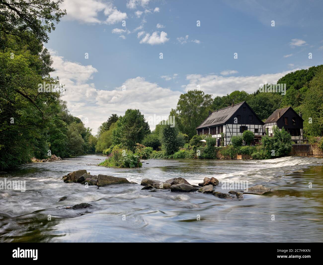 Fiume, mulino, macinazione negozio, casa a graticcio, alberi, foresta, cielo, nuvole, pietre, acqua, corrente Foto Stock