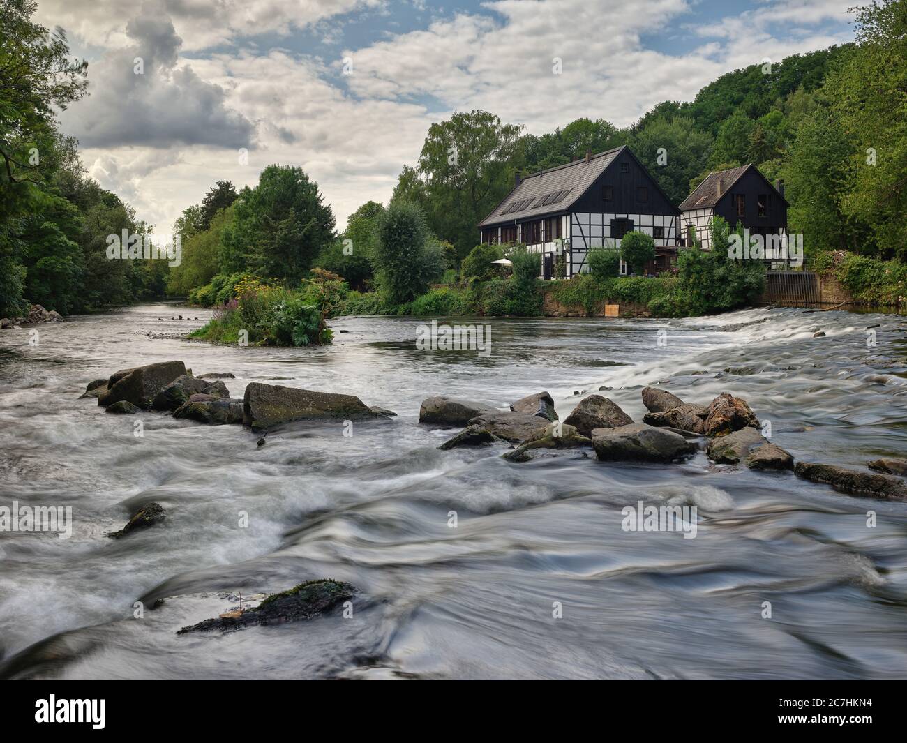 Fiume, mulino, macinazione negozio, casa a graticcio, alberi, foresta, cielo, nuvole, pietre, acqua, corrente Foto Stock