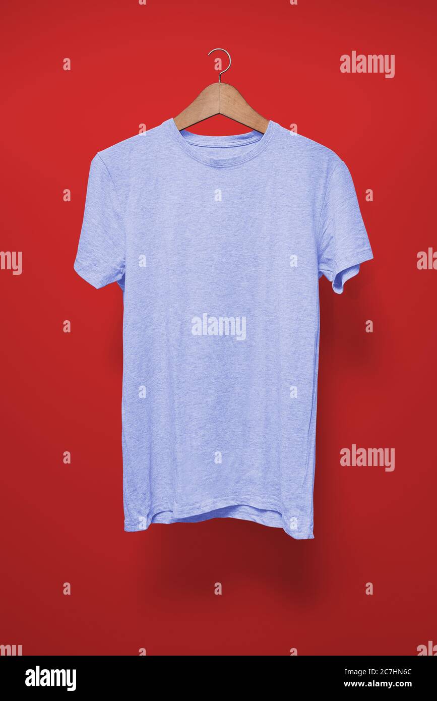 T-shirt azzurro su un appendiabiti su sfondo rosso Foto Stock