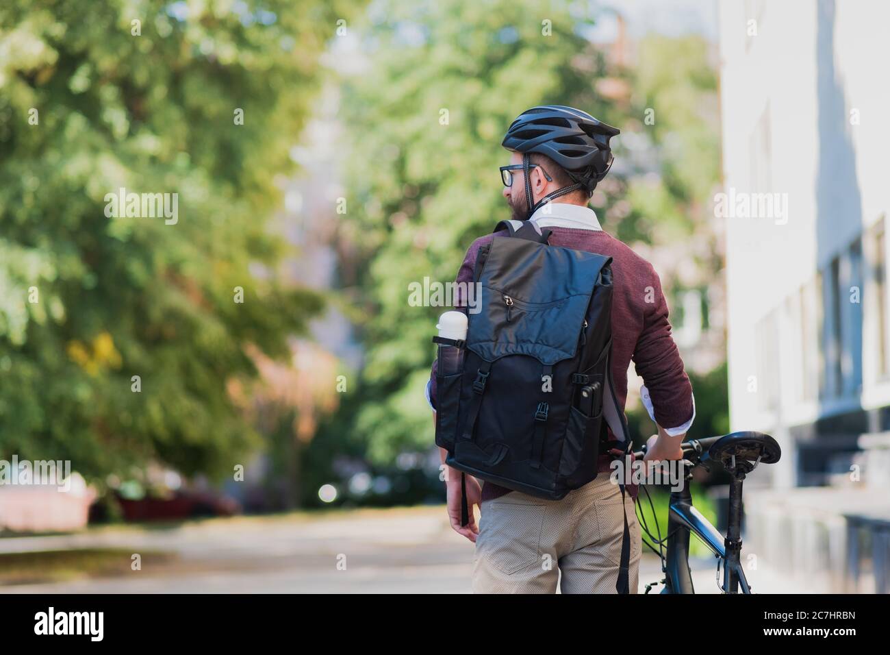 Uomo commuter o messaggero con una bicicletta in ambiente urbano. Pedalare in città, andare a lavorare in bicicletta, immagine uomo di consegna Foto Stock
