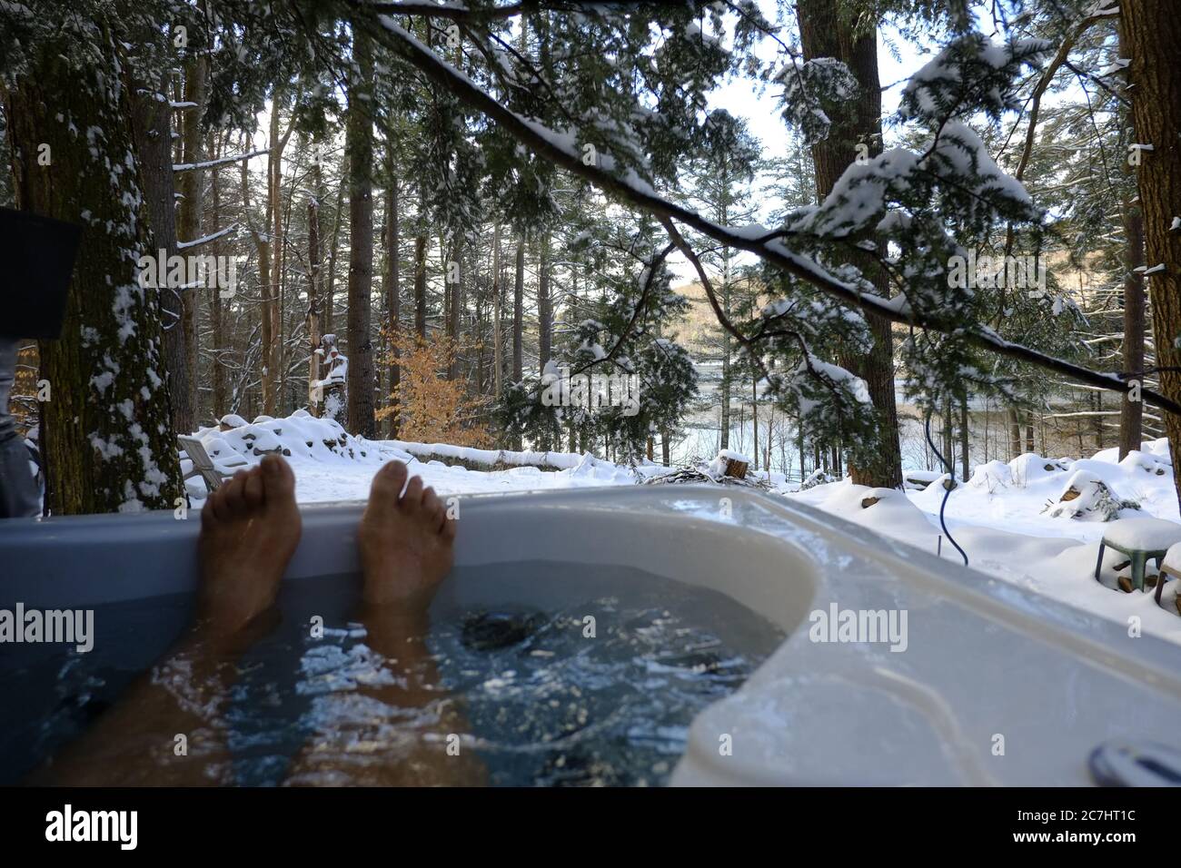 I piedi dell'uomo si stacca dalla vasca idromassaggio all'aperto durante l'inverno Foto Stock