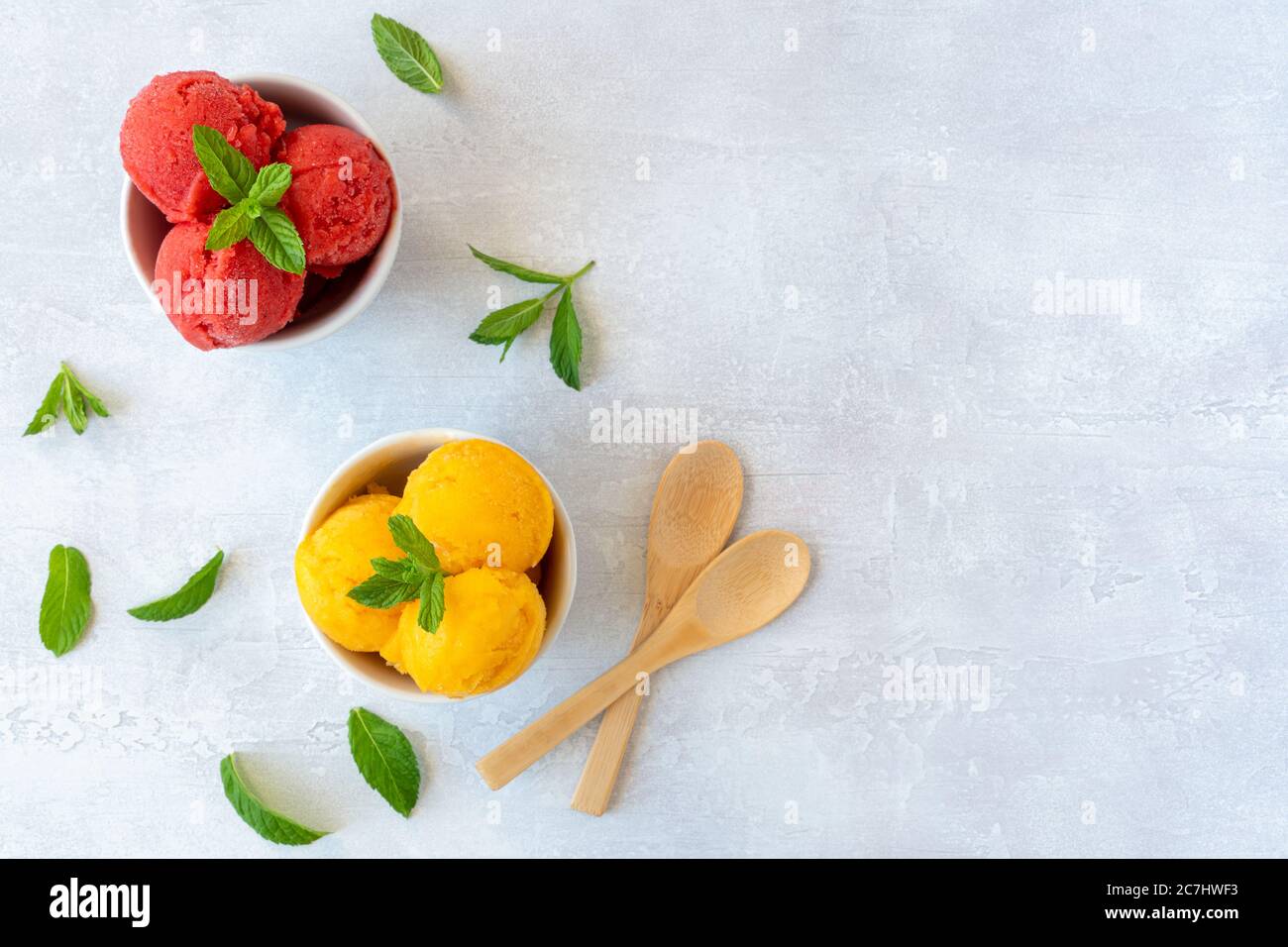 Scoop di gelato in ciotole con fragole e sapori di mango. Vista dall'alto Foto Stock