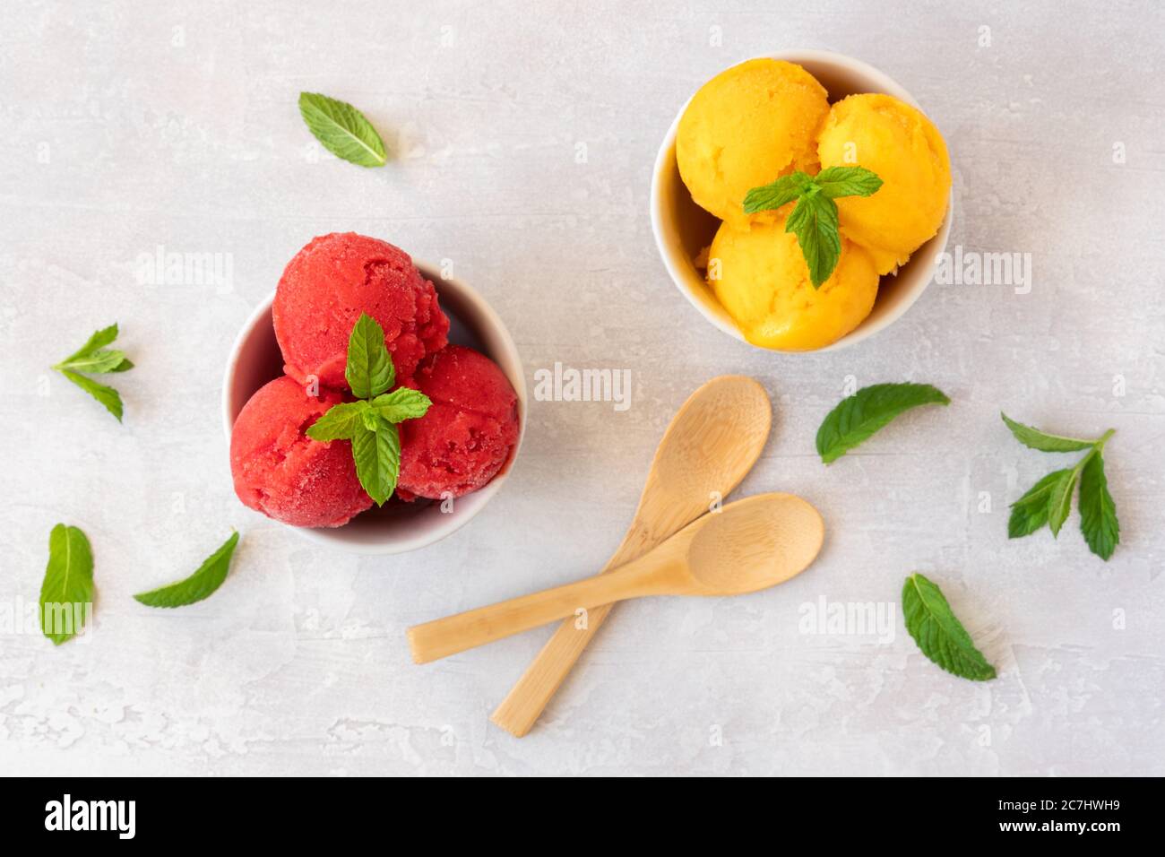 Scoop di gelato in ciotole con fragole e sapori di mango. Vista dall'alto Foto Stock