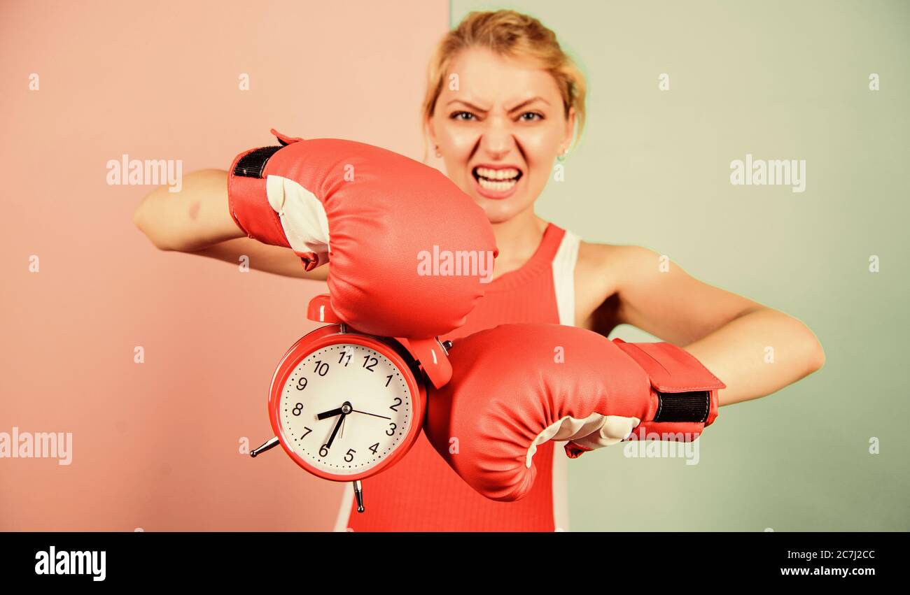 Sportive. vincere il giorno. arrabbiato donna guantoni da pugilato. ragazza boxer tenere premuto il tasto alarm clock. Mattina energia. pieno di potenza. tempo di attività. Che stabilisce il tempo di clock. Il momento di combattere. Il tempo necessario per il successo. Foto Stock