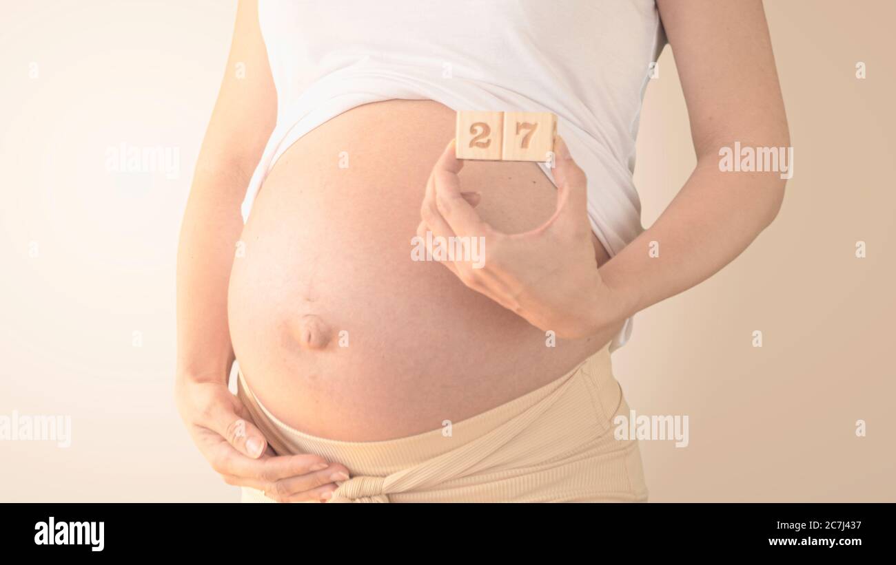 Giovane donna incinta con numero di settimana di gravidanza accanto alla  pancia. Foto della crescita della pancia a 27 settimane di gravidanza.  Dieta sana di gravidanza Foto stock - Alamy