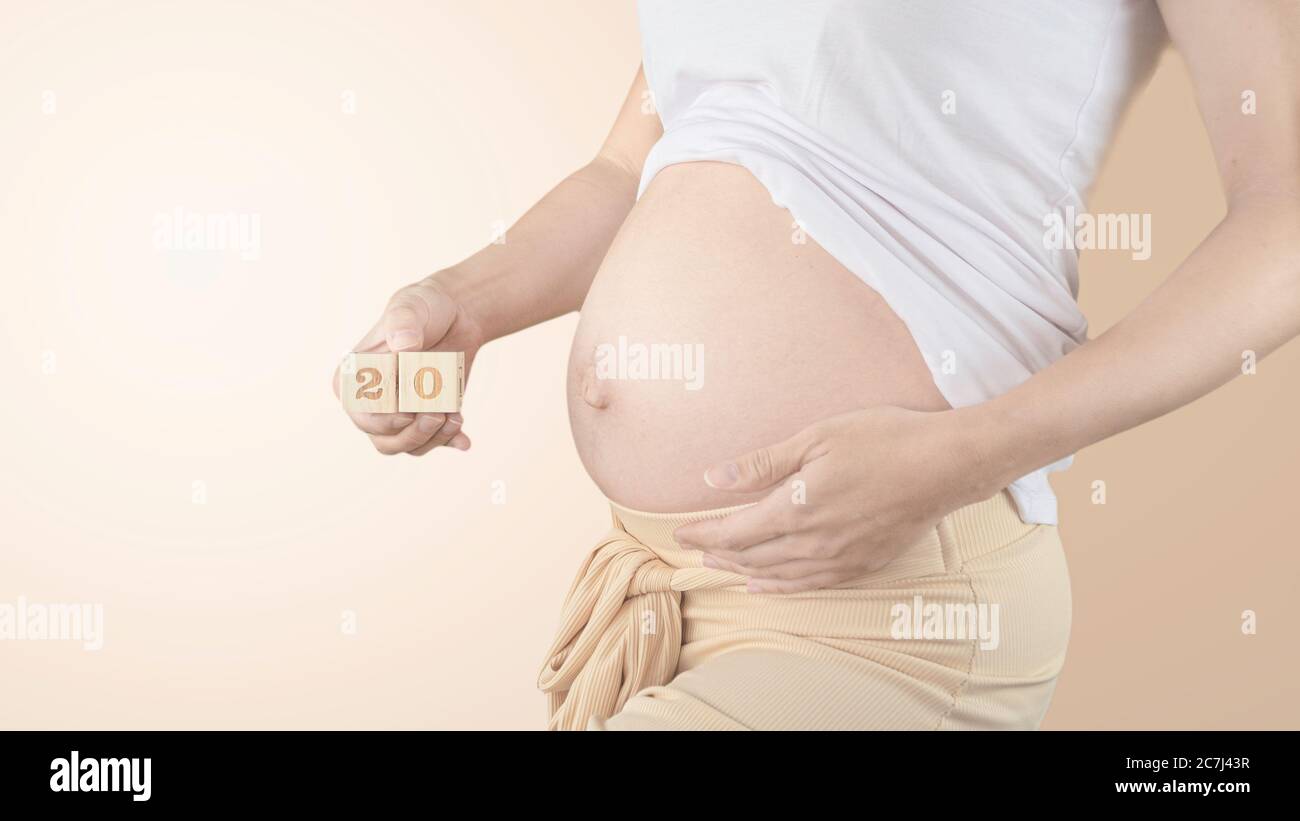 Giovane donna incinta con numero di settimana di gravidanza accanto alla  pancia. Foto della crescita della pancia a 20 settimane di gravidanza.  Dieta sana di gravidanza Foto stock - Alamy