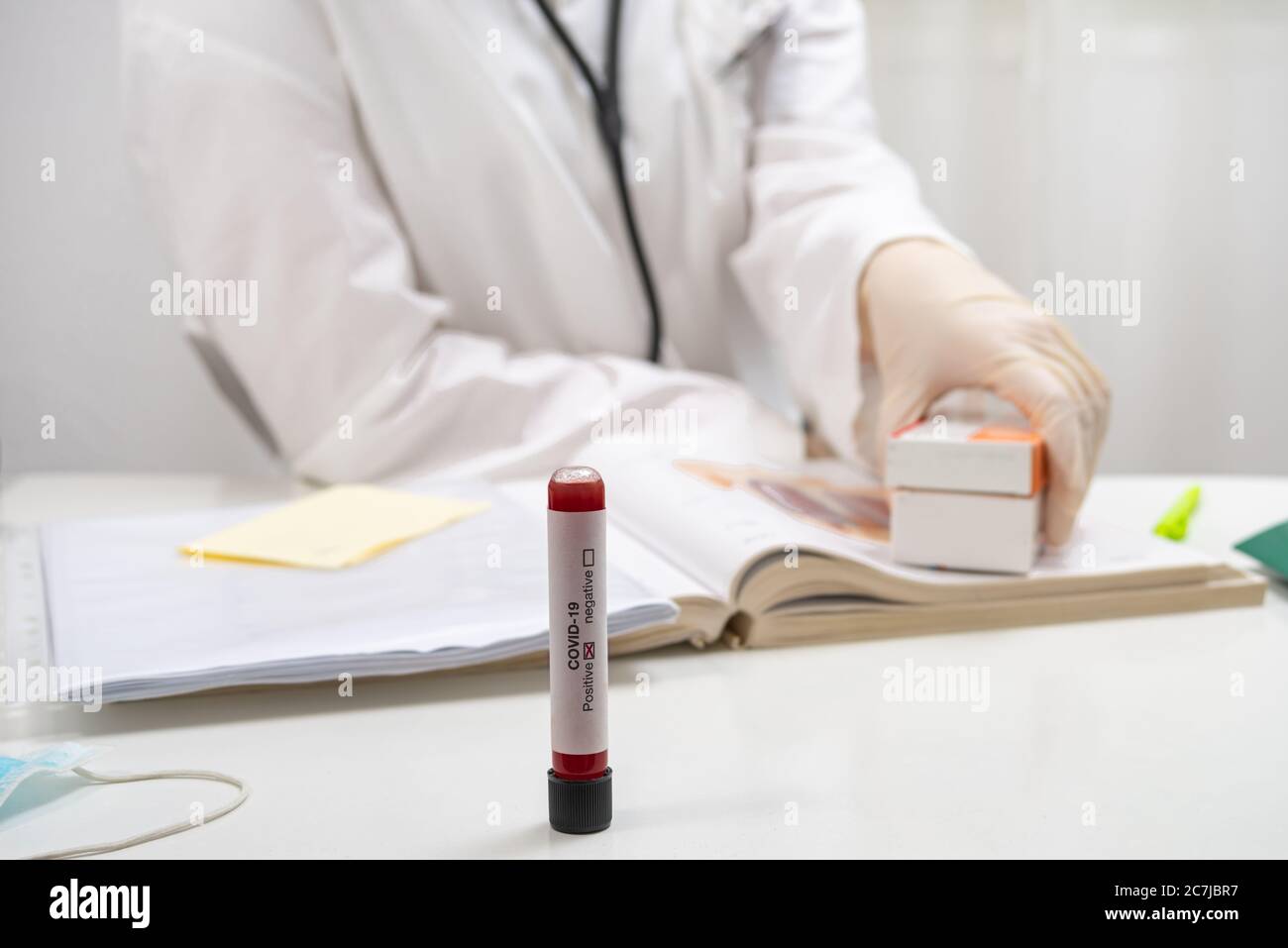 Provetta per analisi del sangue per coronavirus covid-19 presso l'ufficio medico, medico che tiene pillole e compresse in background Foto Stock