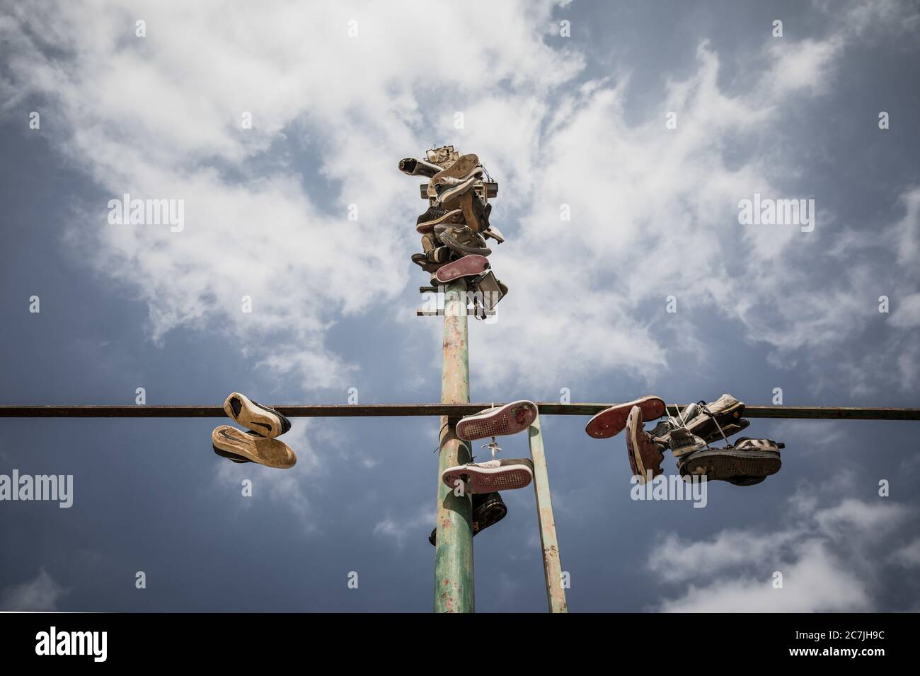 Tiro di scarpe a basso angolo appeso su un tubo di ferro sotto il cielo nuvoloso Foto Stock