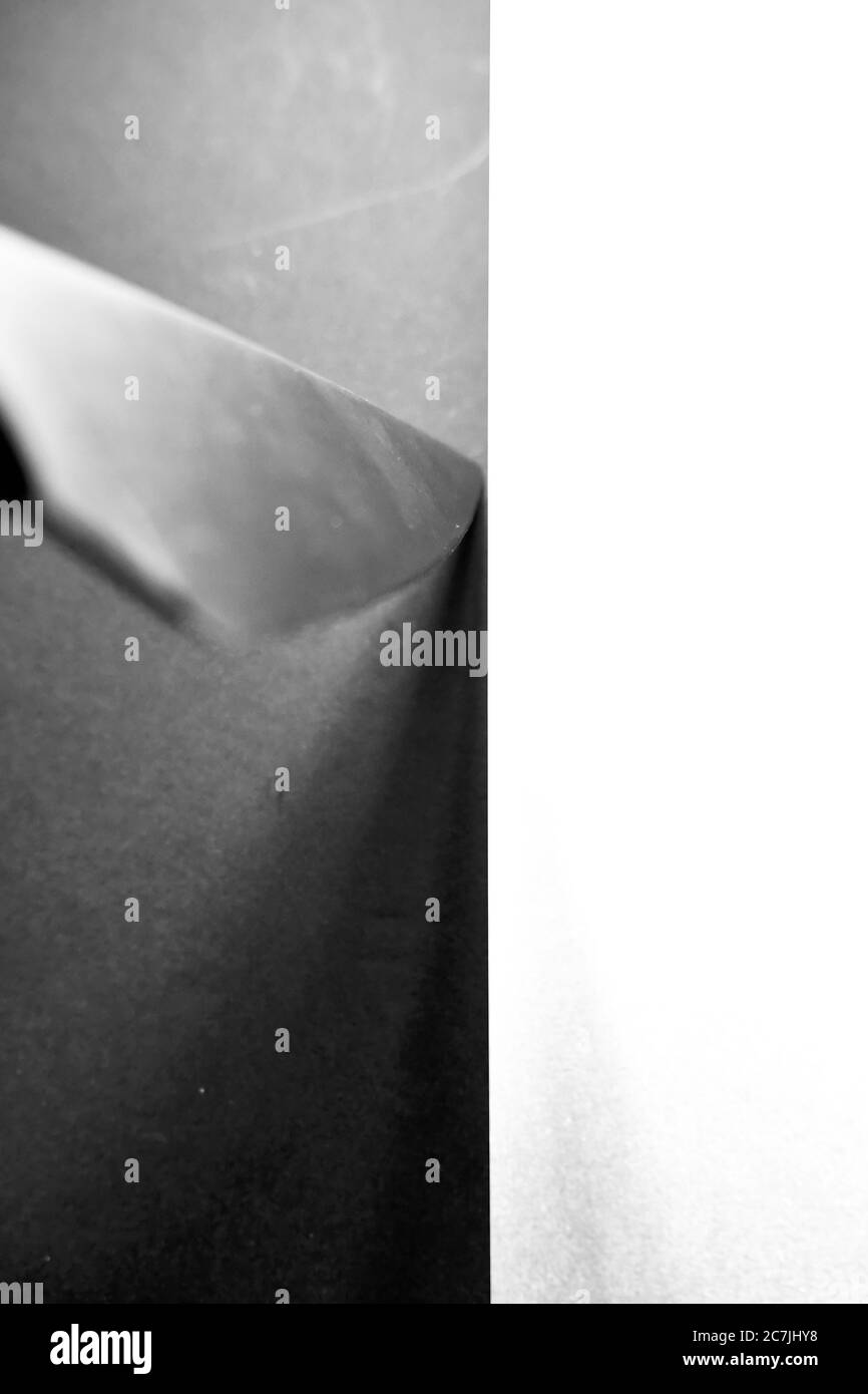 Immagine verticale in scala di grigi di un coltello su un nero e superficie bianca catturata da un angolo elevato Foto Stock