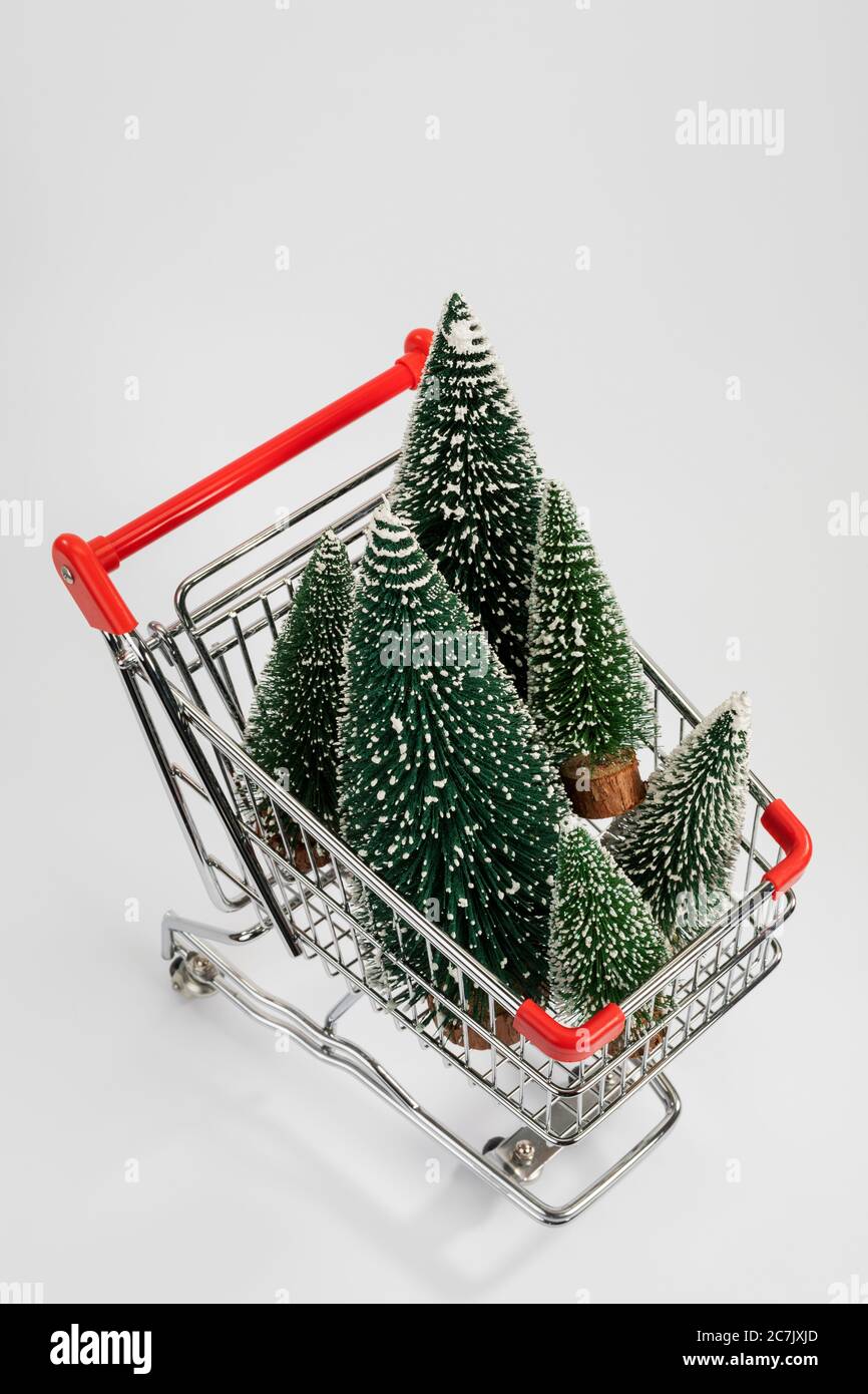 Alberi di Natale in miniatura nel carrello, dall'alto, sfondo bianco, immagine icona, shopping di Natale, Foto Stock
