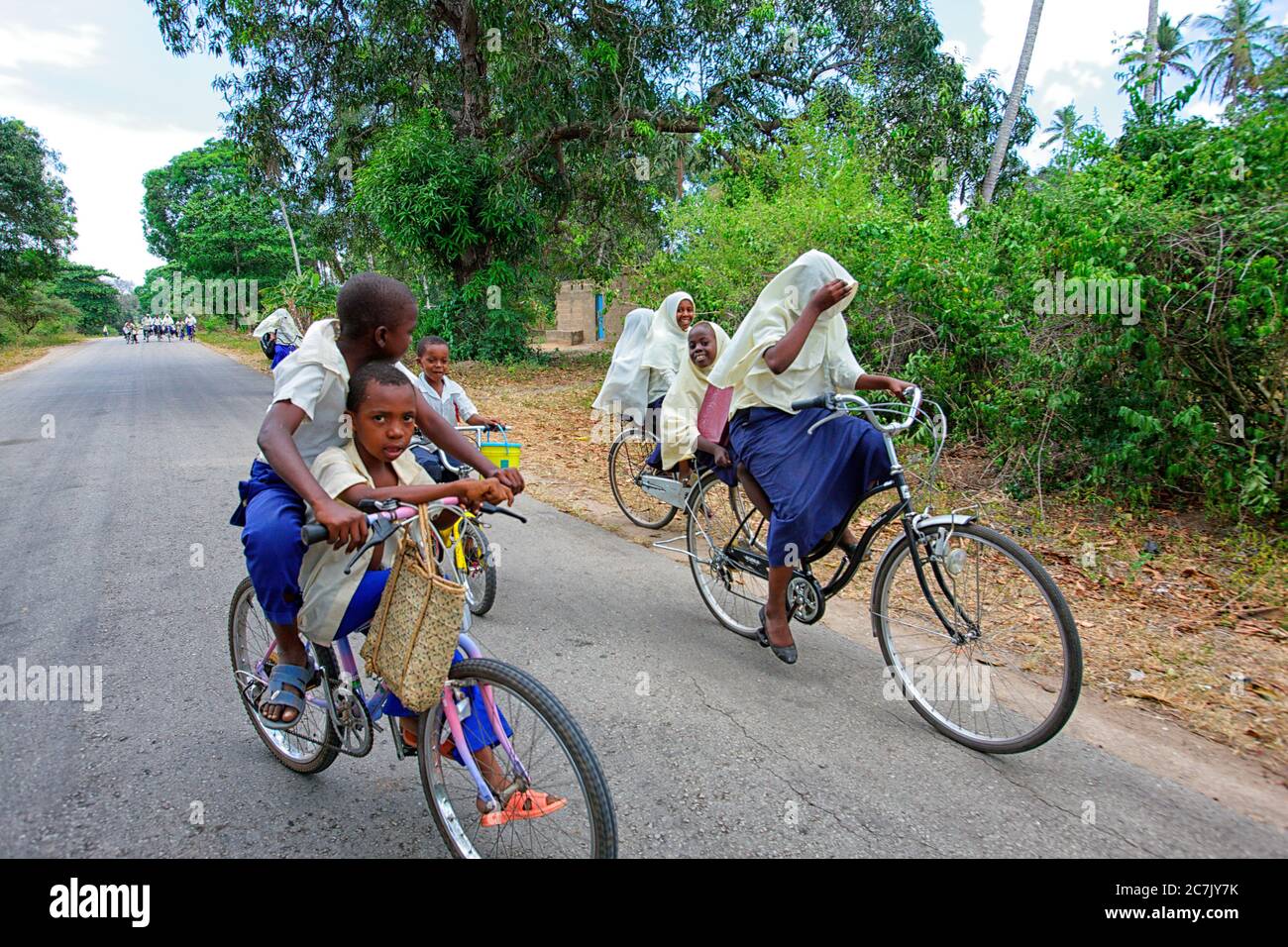 Gli studenti che tornano a casa loro in bicicletta dopo aver terminato la scuola, Zanzibar, Tanzania Foto Stock