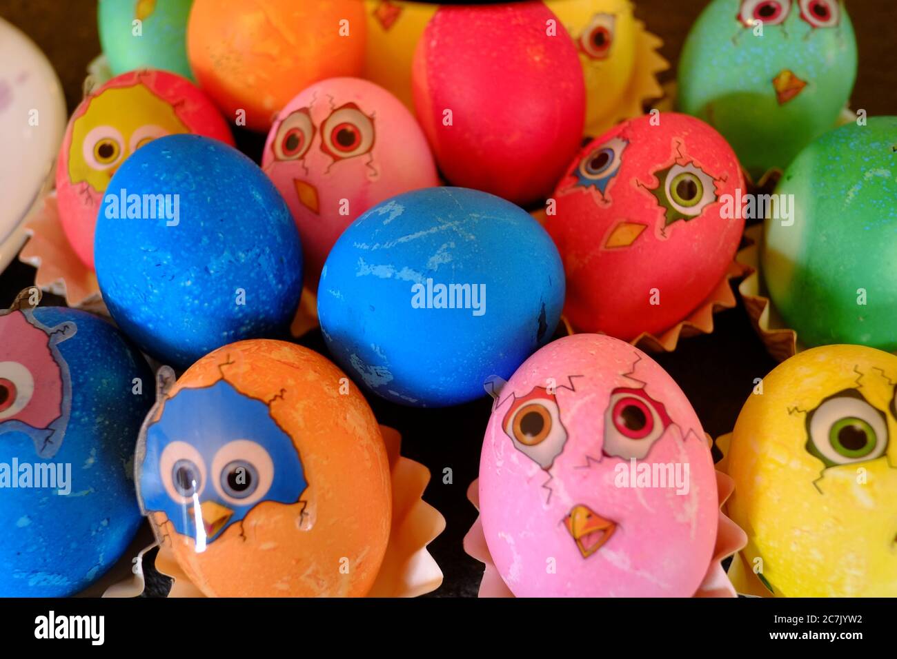 Uova di Pasqua colorate con adesivi che sembrano polli appena sfornati Foto Stock