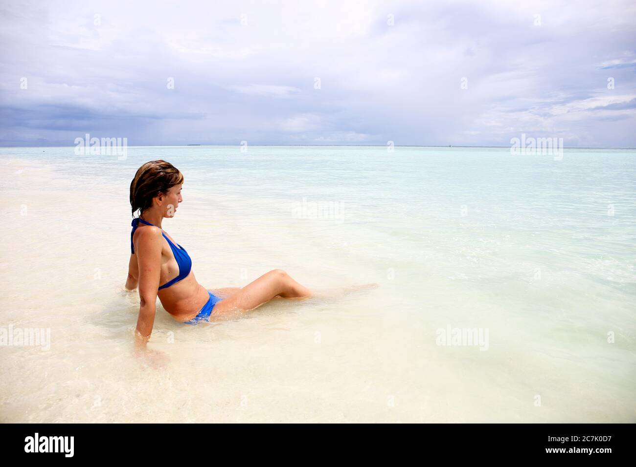 Le Maldive, il ritratto di attraente giovane donna rilassante sulla spiaggia Foto Stock