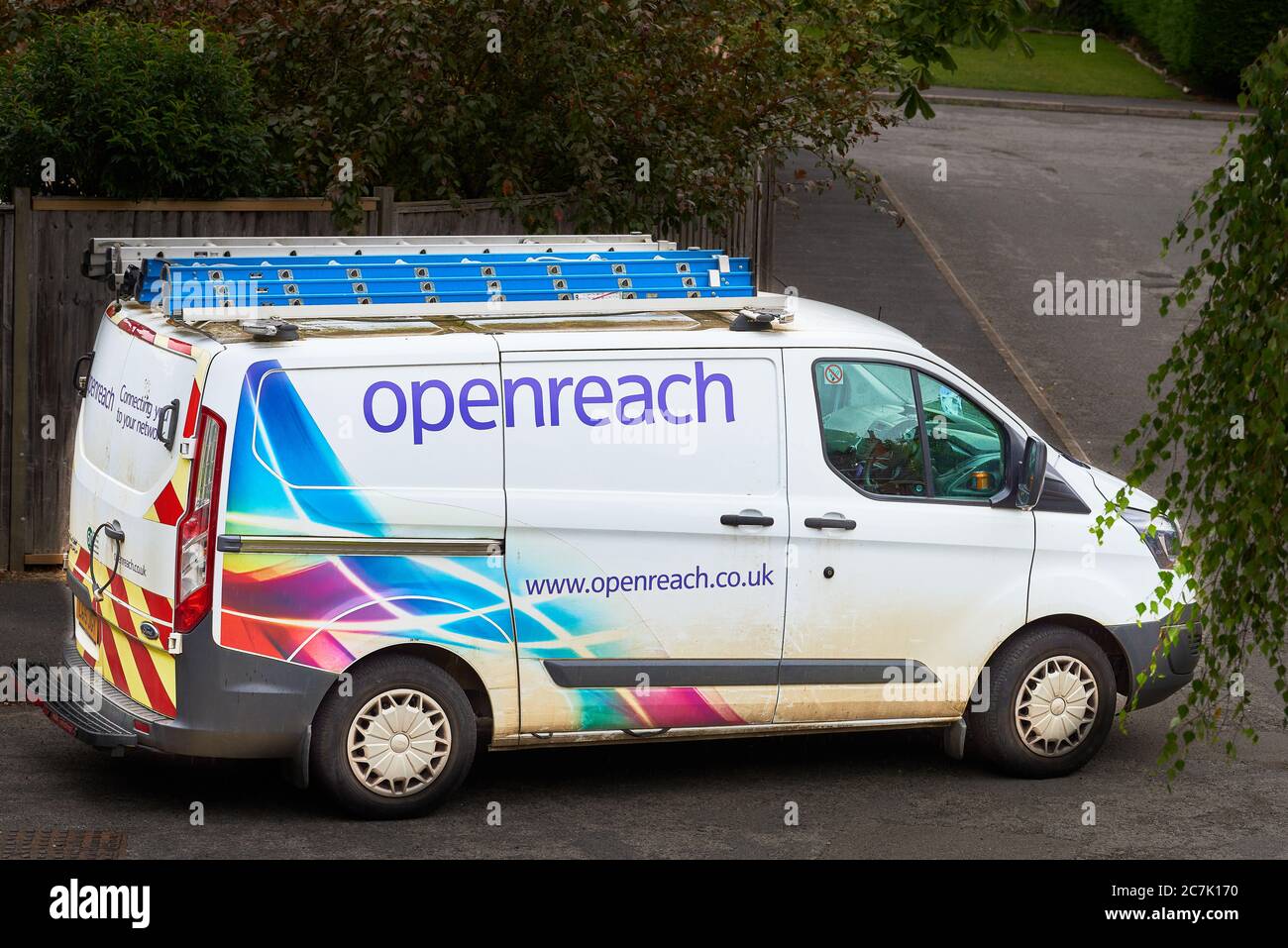 Un furgone BT (con la parola "apriporta" su di esso) parcheggiato mentre un tecnico telefonico ripara un problema di connessione telefonica. Foto Stock