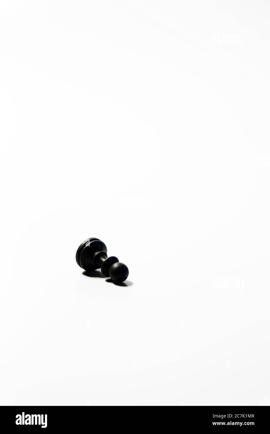Scatto isolato verticale di una pedina di scacchi nera con un sfondo bianco Foto Stock