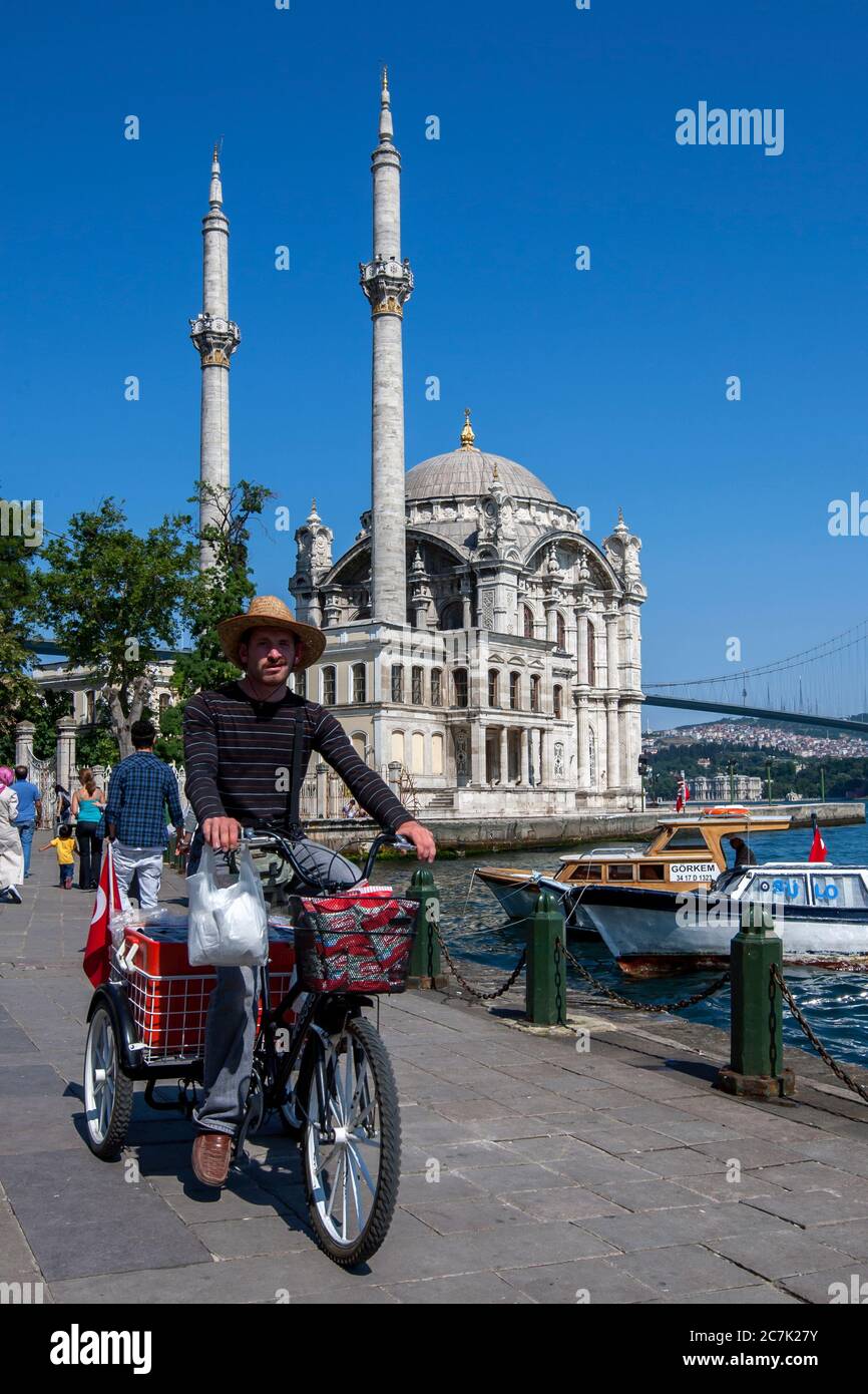 Un uomo passa davanti alla splendida Ortakoy Camii (moschea) che si trova accanto al Bosforo a Ortakoy a Istanbul, in Turchia. Foto Stock