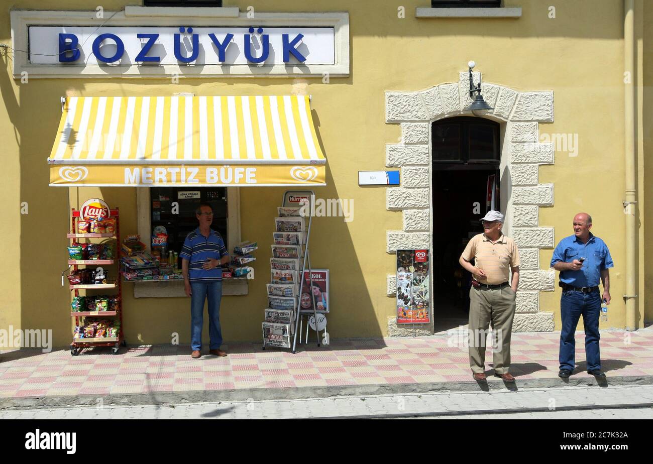 Gli uomini si trovano all'esterno di un negozio situato accanto alla linea ferroviaria di Bozuyuk, nella regione centrale dell'Anatolia in Turchia. Foto Stock
