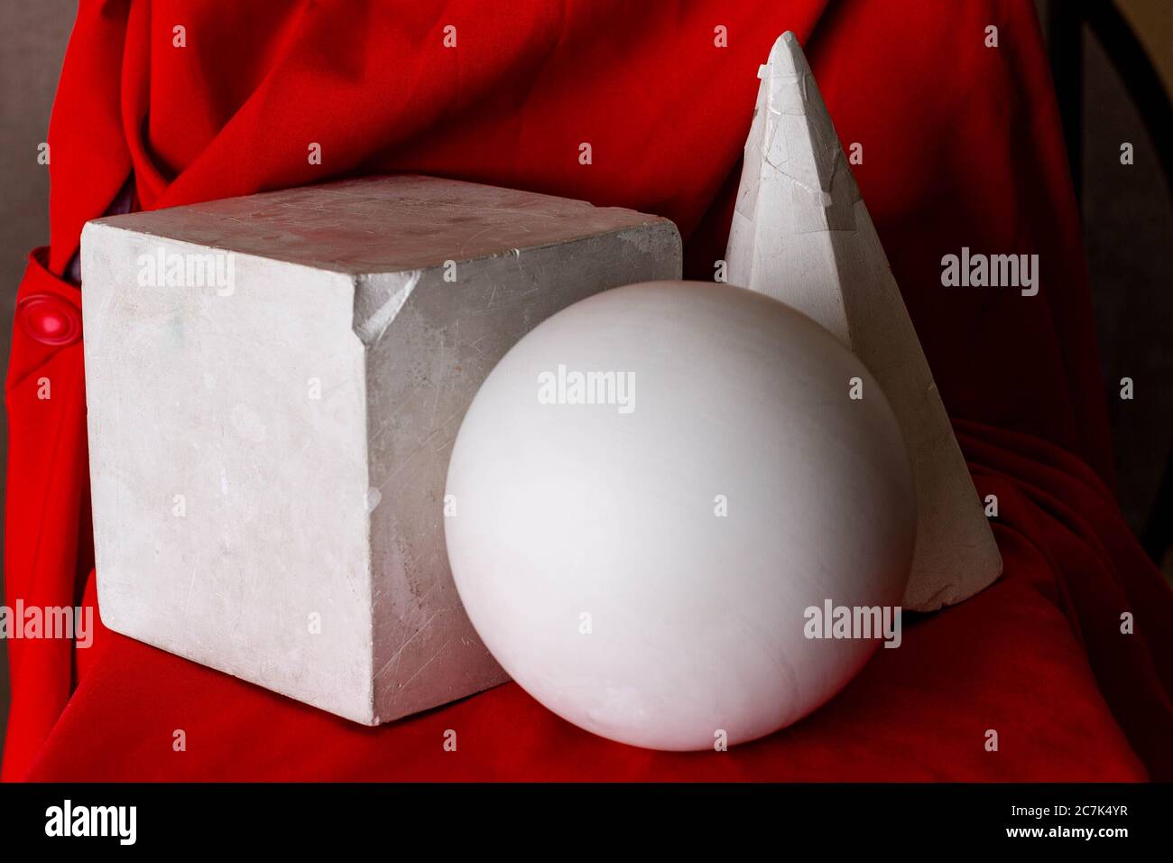 Cubo, palla e cono montati su una sedia rivestita con bellissimi tessuti rossi Foto Stock