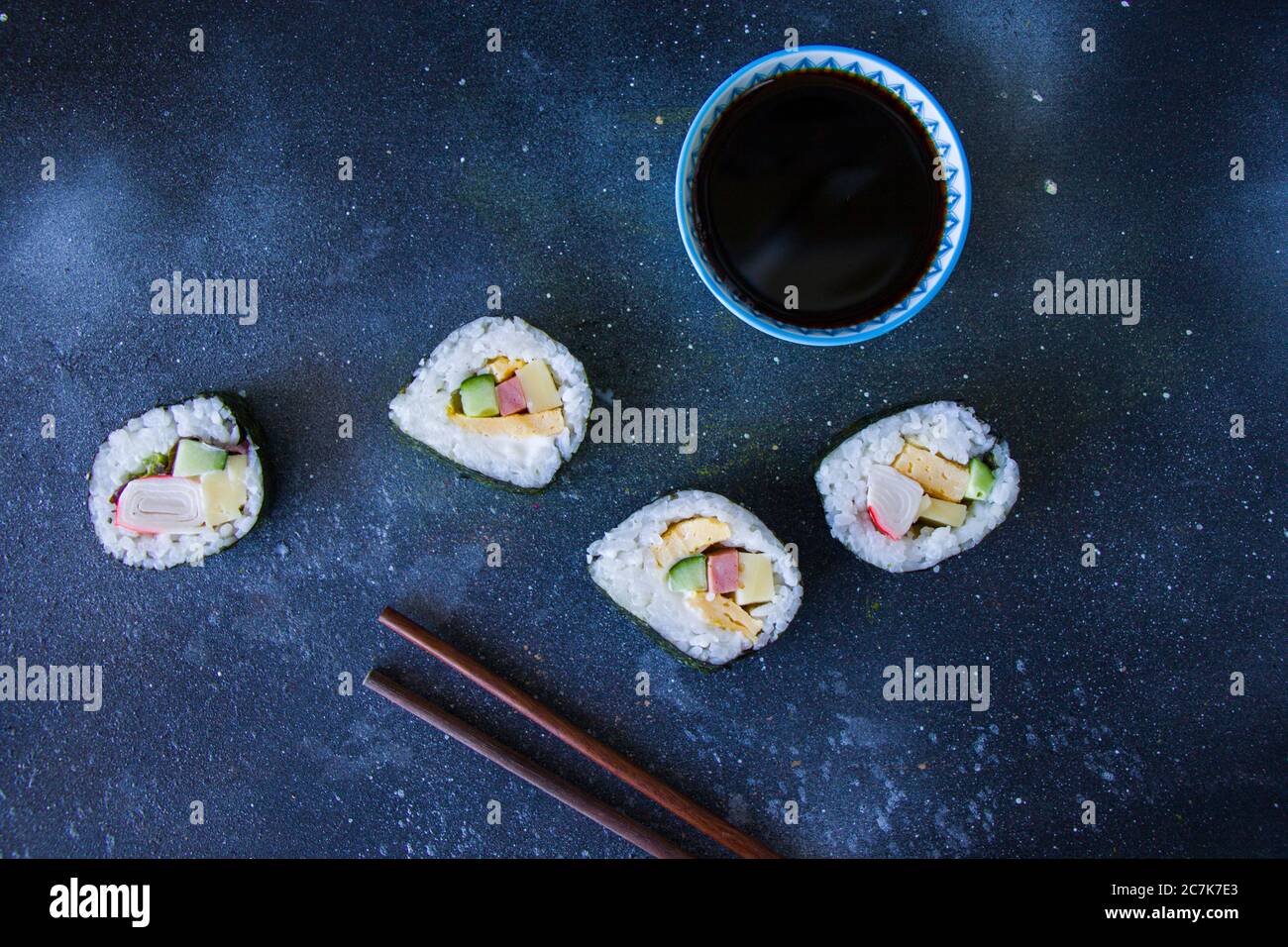 Kimbab o kimbap su sfondo blu con soy souse, sfondo blu, riprese in studio, luce naturale. Foto Stock
