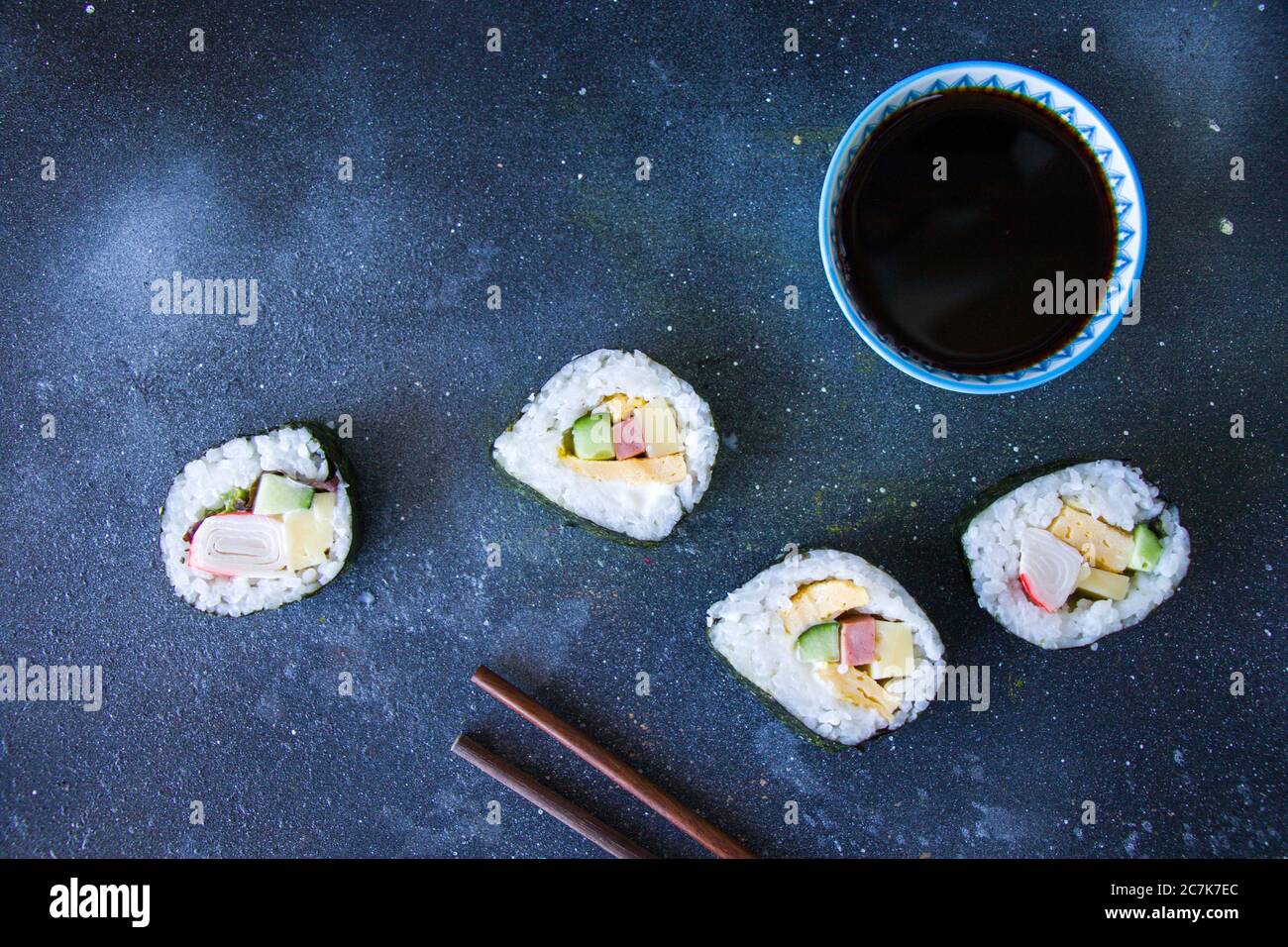 Kimbab o kimbap su sfondo blu con soy souse, sfondo blu, riprese in studio, luce naturale. Foto Stock