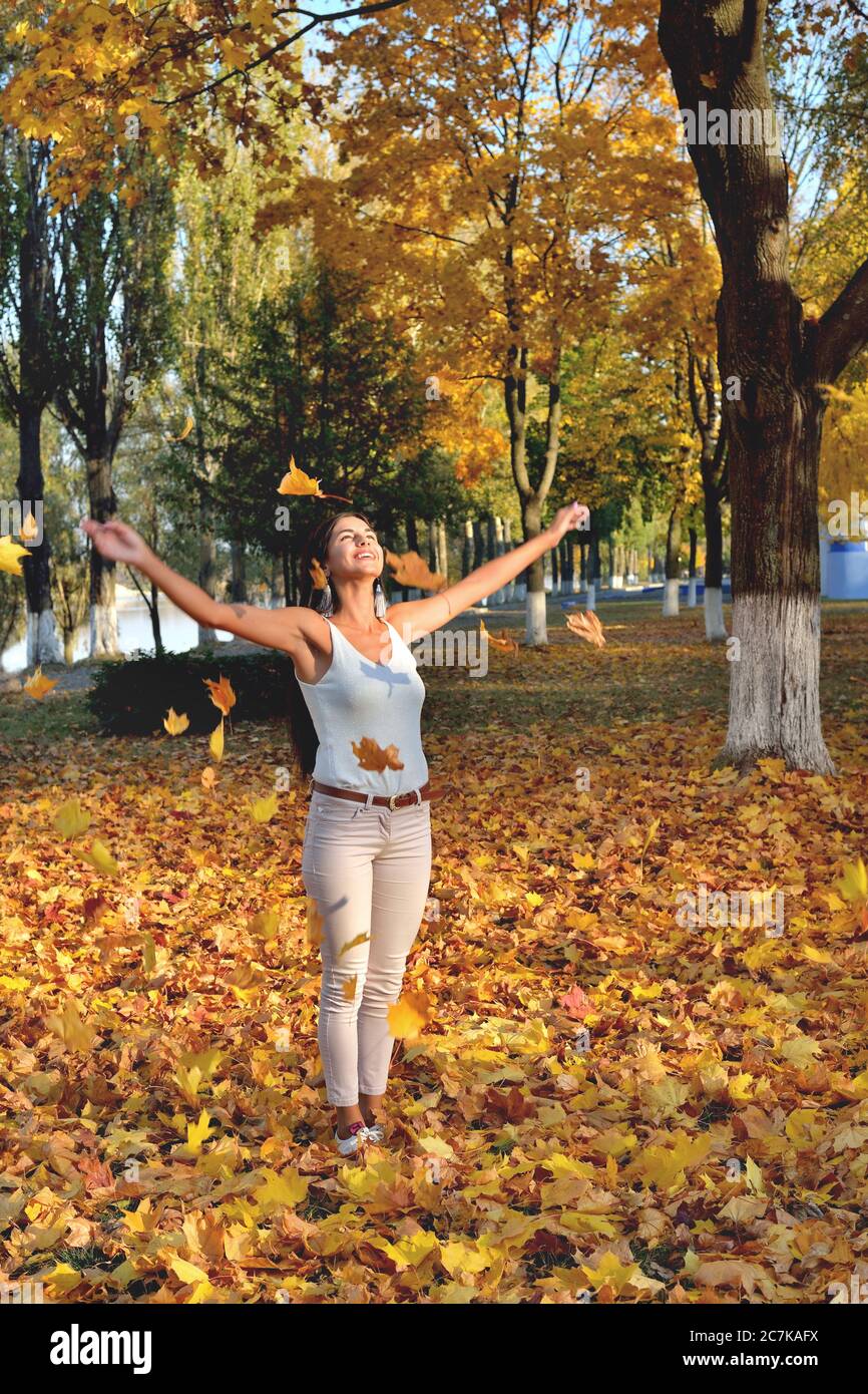 la ragazza ha gettato le foglie di autunno gialle, gli ordini e i giochi nel parco, giorno di sole, sorriso, risata e buon umore, primo piano Foto Stock