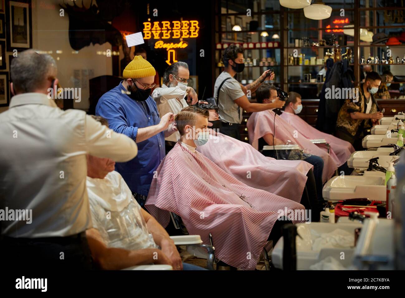 Barbiere di Manchester con lavoratori e clienti che indossano maschere di copertura Foto Stock